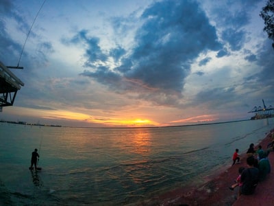 日落时在海上钓鱼的人